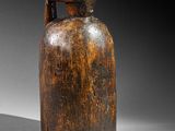an old wooden bottle with a handle sitting on a white surface