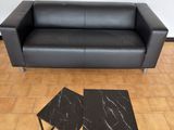 un canapé en cuir noir et deux tables dans un salon