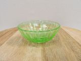 a green glass bowl sitting on a wooden table