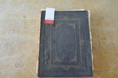 un vieux livre posé par terre, avec une étiquette dessus