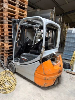 un chariot élévateur garé à côté d'une pile de palettes
