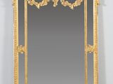 un miroir richement décoré, avec un cadre doré, accroché à un mur blanc