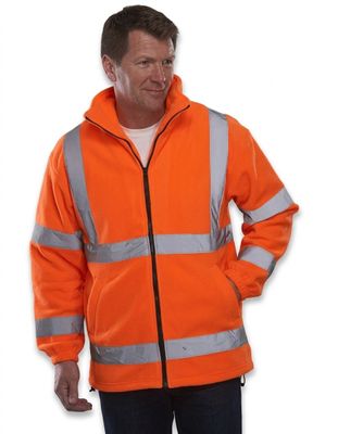 un homme vêtu d'une veste orange, debout, les mains dans les poches