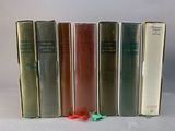 several books are lined up in a row on a white surface