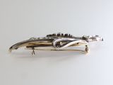 a silver and gold brooch on a white surface