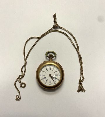 une montre de poche en or avec une chaîne, posée sur une surface blanche