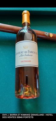une bouteille de vin posée sur une table de billard, à côté d'une queue de billard