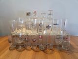 bottles and glasses are lined up on a table in front of a white wall