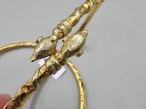 someone is holding a gold bracelet with two birds on it