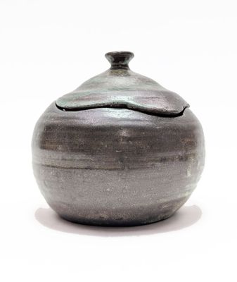 a small gray vase with a lid sitting on a table