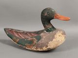 un vieux canard en bois posé sur une surface grise