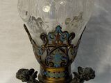 a glass vase with a statue on it on a table