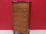 an image of a small wooden chest of drawers against a red wall