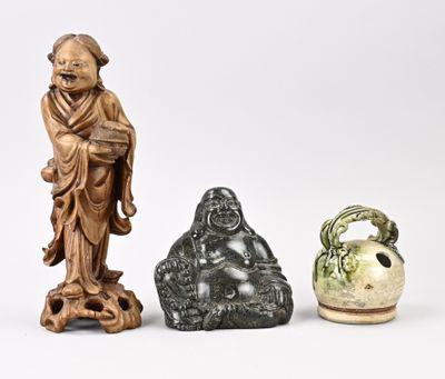 Trois figurines asiatiques sont assises les unes à côté des autres sur une surface blanche
