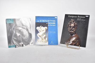 trois livres posés sur une table blanche, accompagnés d'une statue d'homme et d'une statue de femme
