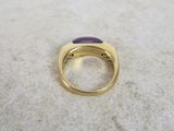 a close up of a gold ring with a purple stone in it