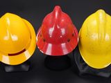 three yellow and red hard hats sitting next to each other on a black surface
