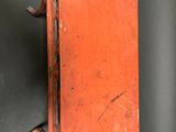 an old red suitcase with a handle hanging on a wall