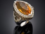 an orange sapphire and diamond ring on a black surface