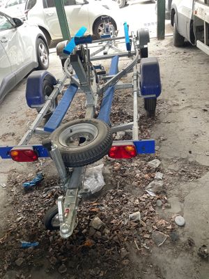 un petit bateau sur une remorque, garé sur un parking