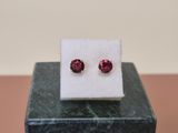 a pair of ruby colored stone stud earrings sitting on top of a marble block