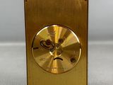 a gold clock that is sitting on a white surface