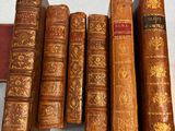 Plusieurs vieux livres sont alignés sur une table à côté d'une bibliothèque.