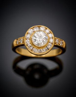 une bague en or jaune sertie d'un diamant rond entouré de petits diamants