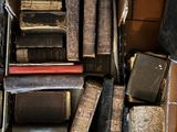 a pile of old books on the floor next to a pile of luggage