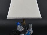 une paire d'oiseaux bleus posés sur un socle en acrylique transparent, avec un abat-jour blanc