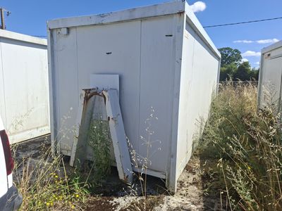 une cabane de toilettes blanche au milieu d'un champ