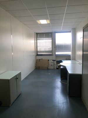 une pièce avec un bureau, des armoires et une fenêtre