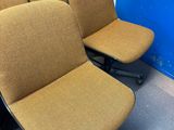 Dans une pièce, plusieurs chaises sont alignées contre un mur bleu