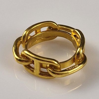 a gold ring with a chain on it on a white surface
