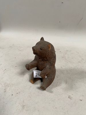 une petite figurine d'ours assise par terre, avec une étiquette de prix