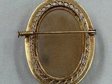 a picture of a gold brooch on a white surface