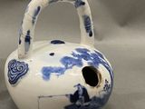 a blue and white vase with a handle on a table