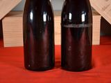 two bottles of wine sitting on a red table cloth