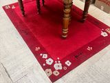 une image représentant une table avec un tapis rouge posé au sol