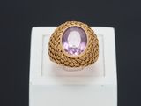 Gros plan sur une bague en or ornée d'une pierre violette.