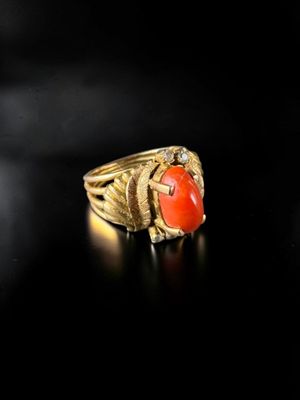a close up of a gold ring with a red stone