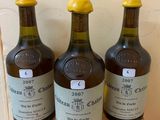 three bottles of wine sitting on a wooden shelf in front of a wall