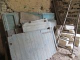 a ladder leaning against a wall next to a pile of old doors