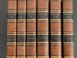 six vieux livres sont alignés sur une surface noire