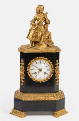 une horloge noire et dorée surmontée d'une statue