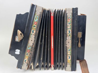 an old black accordion sitting on top of a wooden stand
