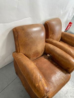 fauteuil inclinable en cuir marron avec accoudoirs, adossé à un mur blanc