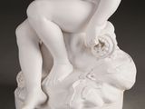 a white statue of a boy sitting on a rock