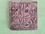 an old silver coin with writing on it sitting on a green surface