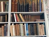 many books on a bookcase with a clock above them